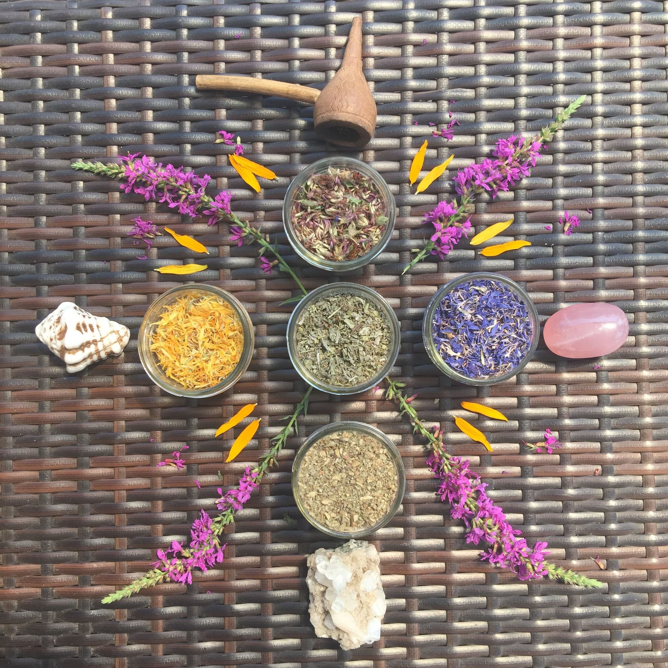 Herbal remedies in small bowls with flowers on a woven surface