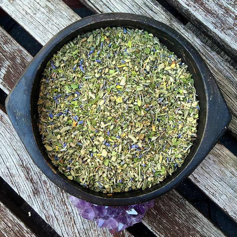 Bowl of CALM Herbal Blend showing organic calming herbs on wood panel with amethyst