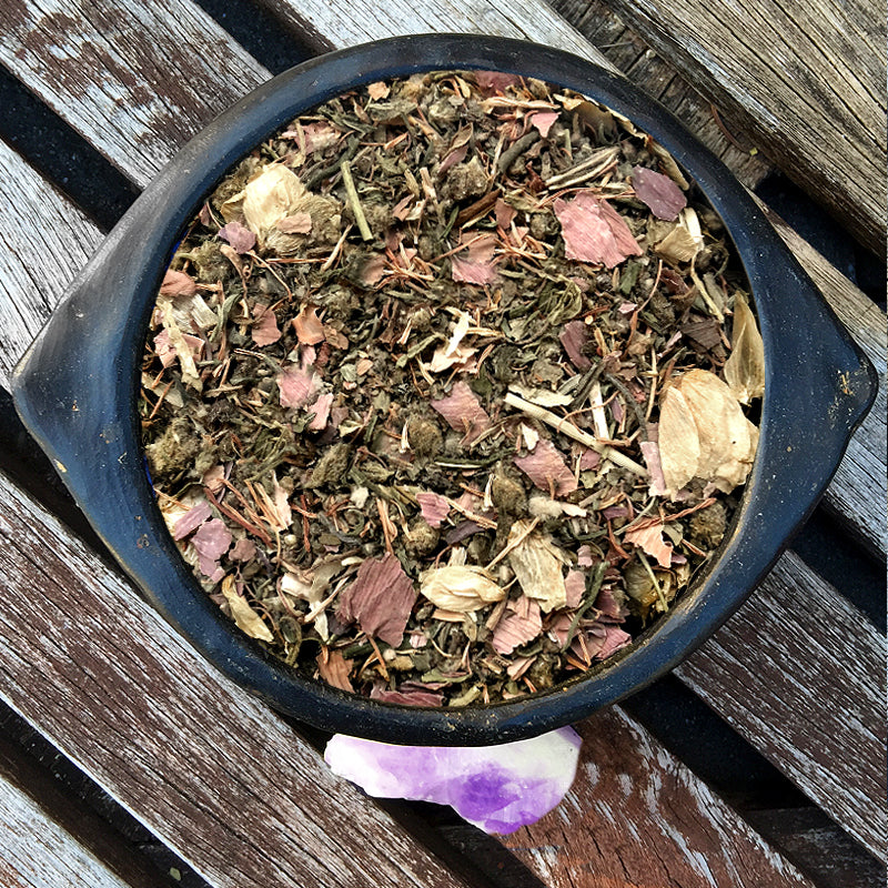 Herbal tea mix in a black pot on a wooden surface