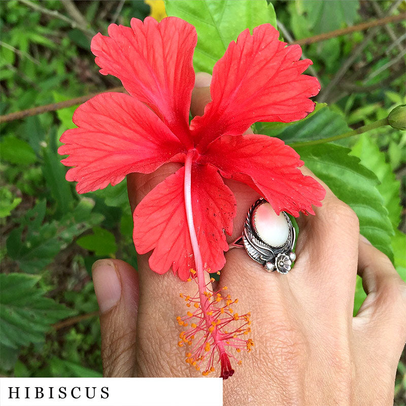 Hand with opal silver ring holding a hibiscus blossom from FEMME blend