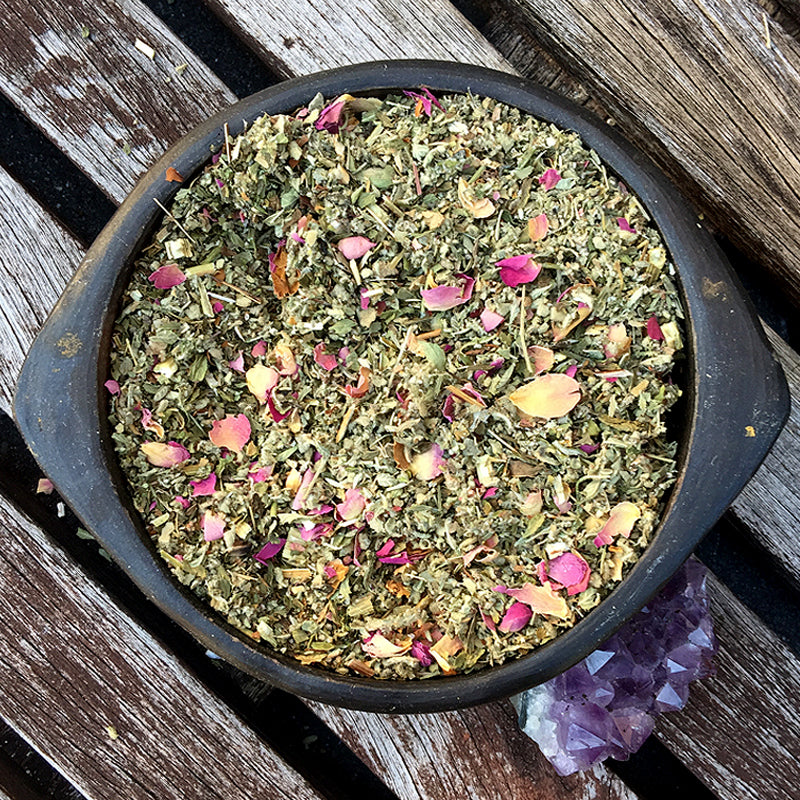 Pink and green herbs in a black bowl on wooden panels – SYNC herbal mix