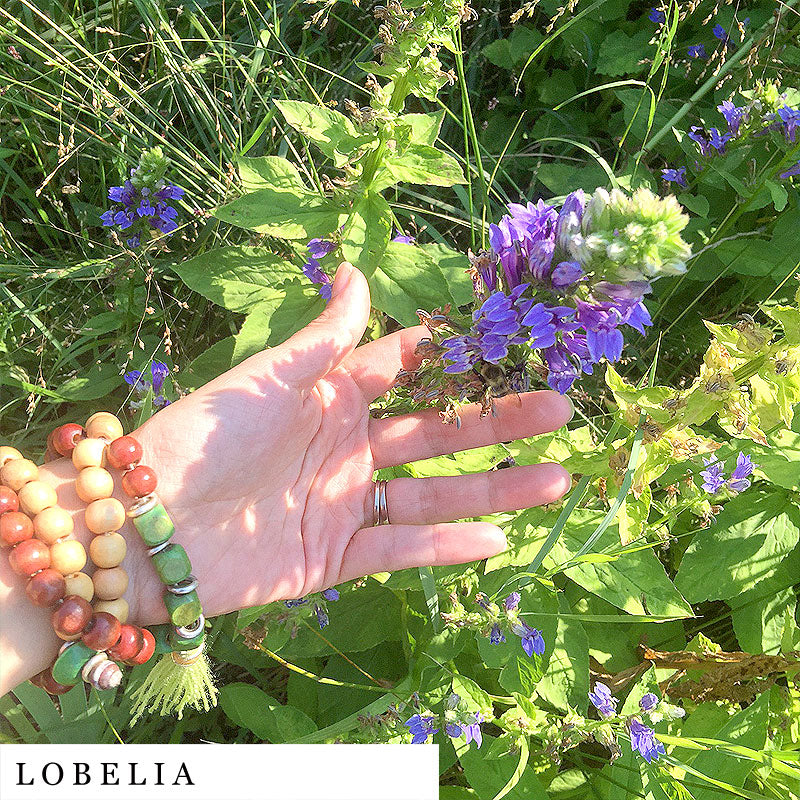 Purple lobelia flowers held by a girl’s hand – ingredient in QUIT herbal blend