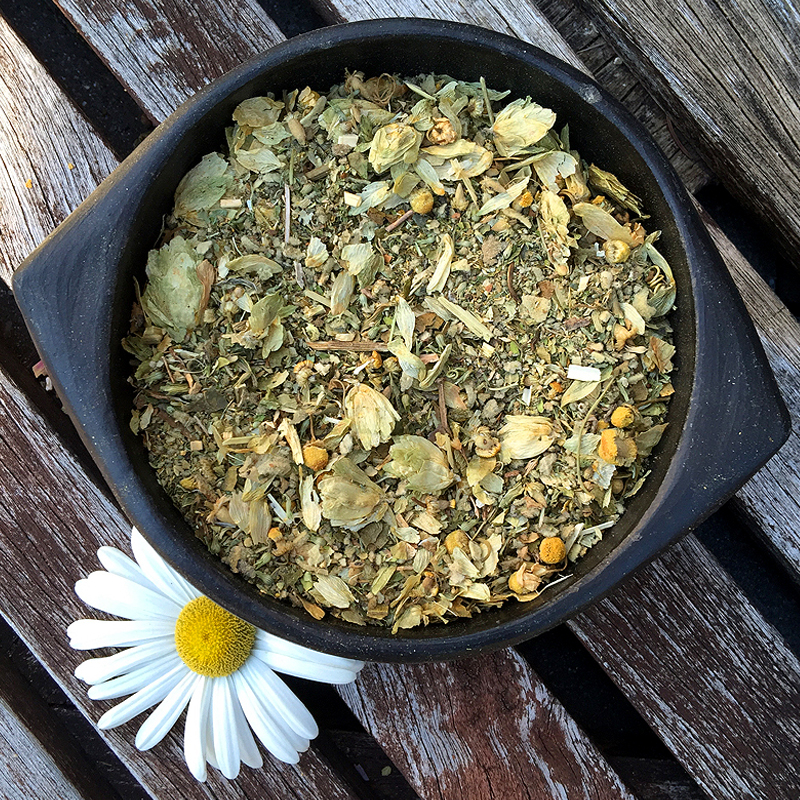 Ceramic bowl with a botanical mix of chamomile, hops, Passion flower and mullein over a daisy flower. 