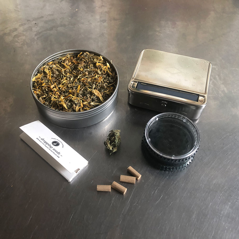 Step 1 Gather your herbal tin with rolling papers, grinder and rolling box on a steel table.