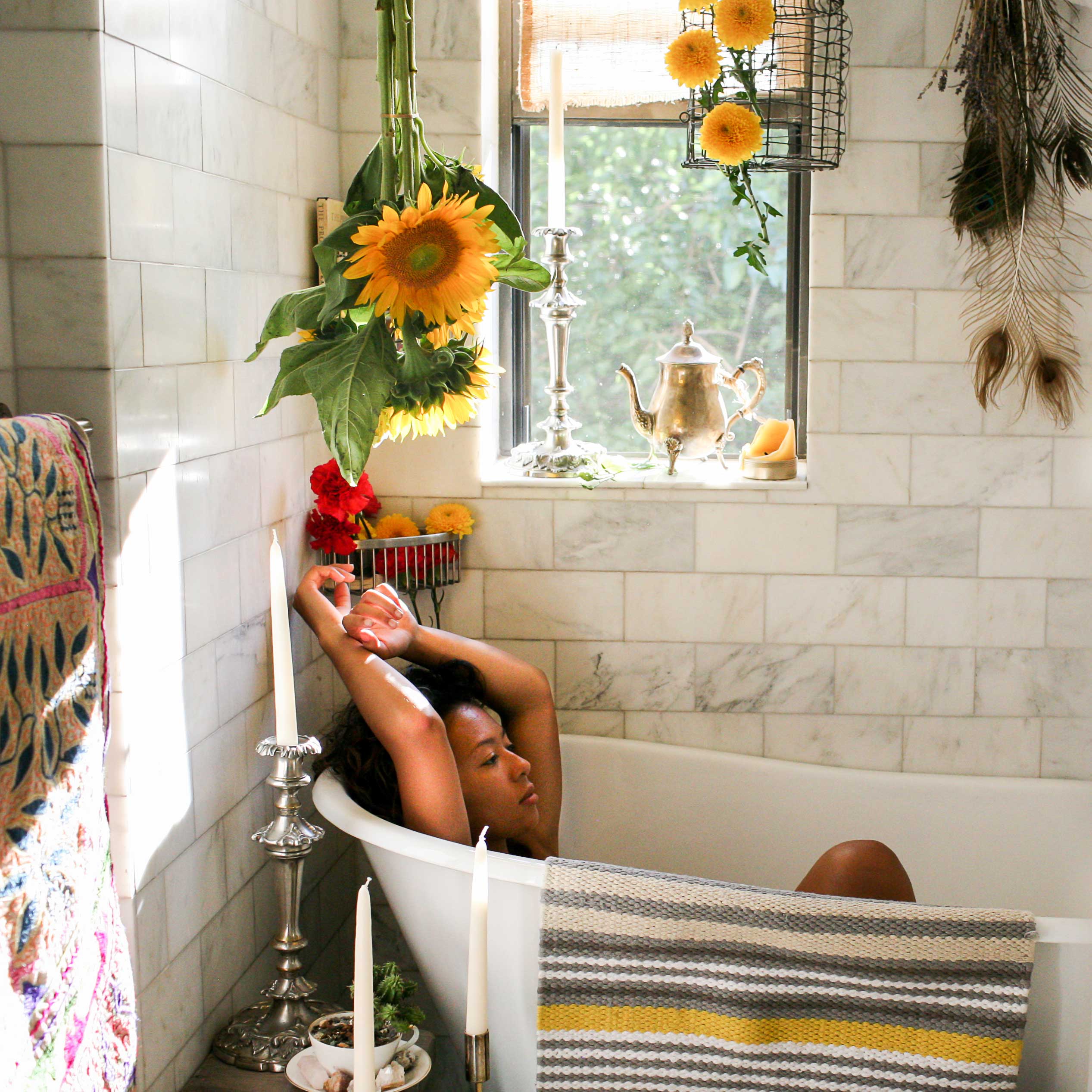 Girl in a botanical herbal bath surrounded by flowers and candles.
